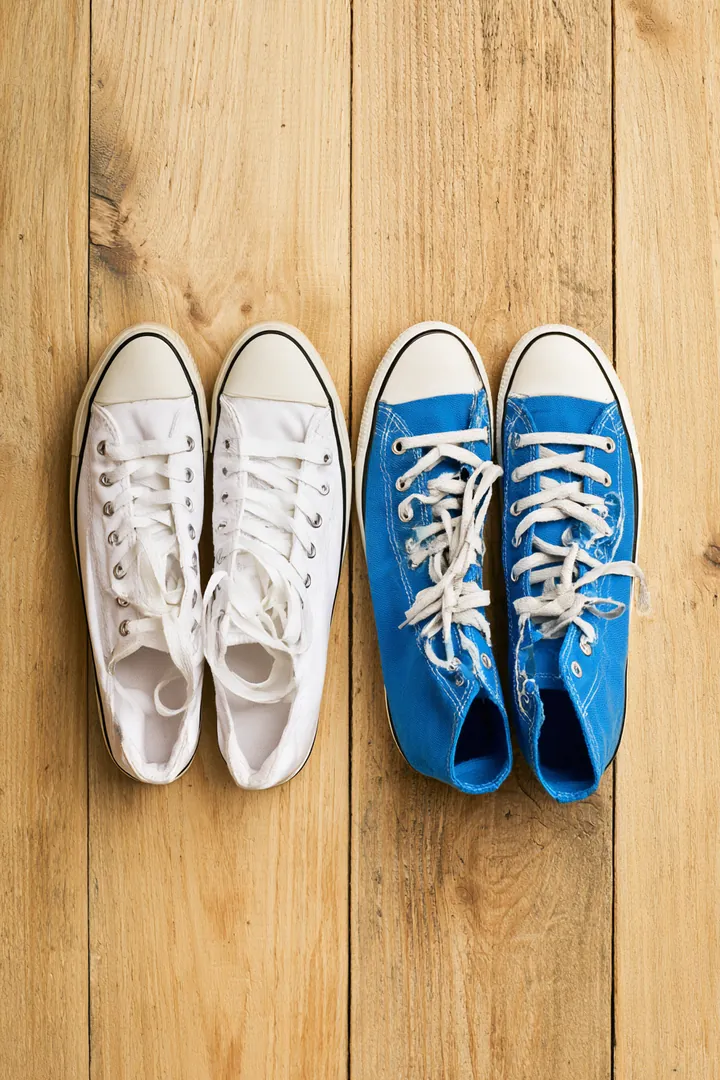 Two pairs of sneakers, one white and one bright blue, side by side on a light wood floor, like two loan offers compared