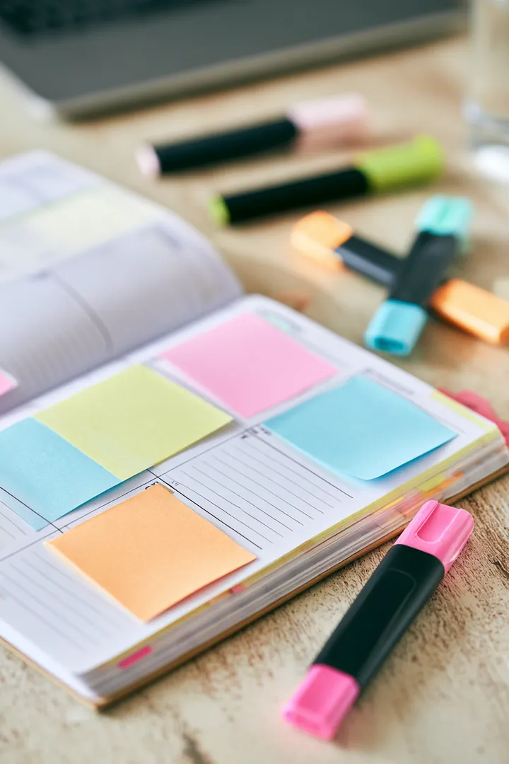 Open weekly paper planner with color-coded sticky notes and highlighters, mapping out an amone loan payoff plan
